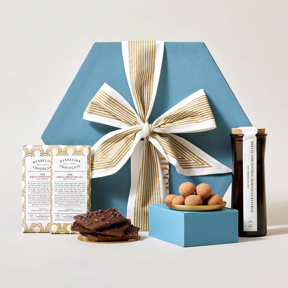 Gift box with a ribbon, cookies, and snacks arranged attractively.