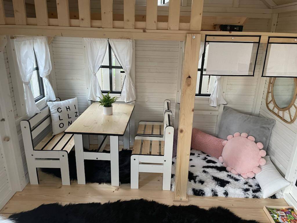 Inside of decorated kids playhouse with kids furniture, bean bags and rugs by WholeWoodPlayhouses