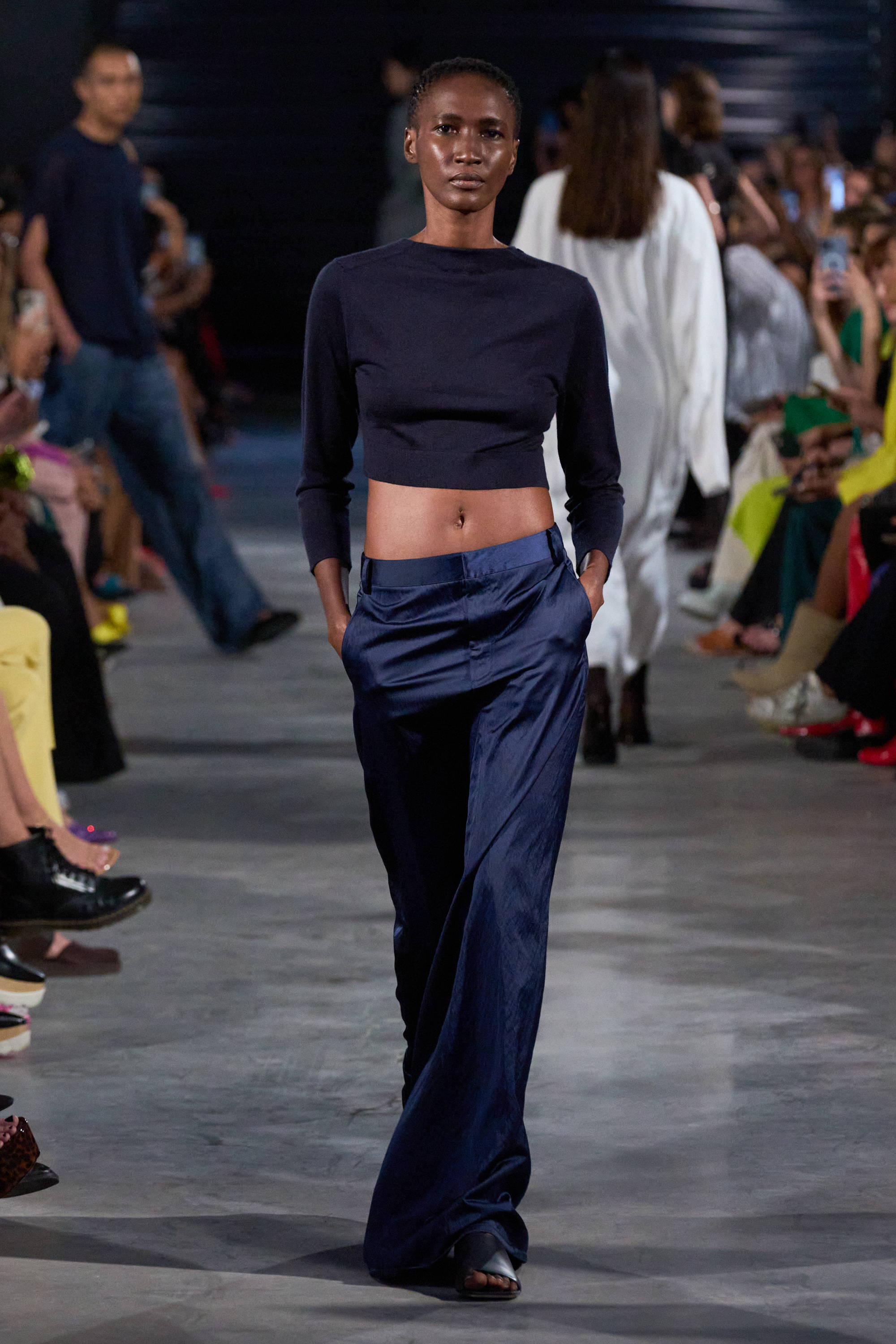 Model on a runway wearing crop sweater and shiny pants