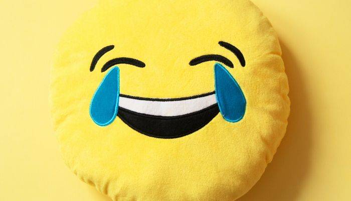 A stuffed cry laughing yellow smiley face pillow