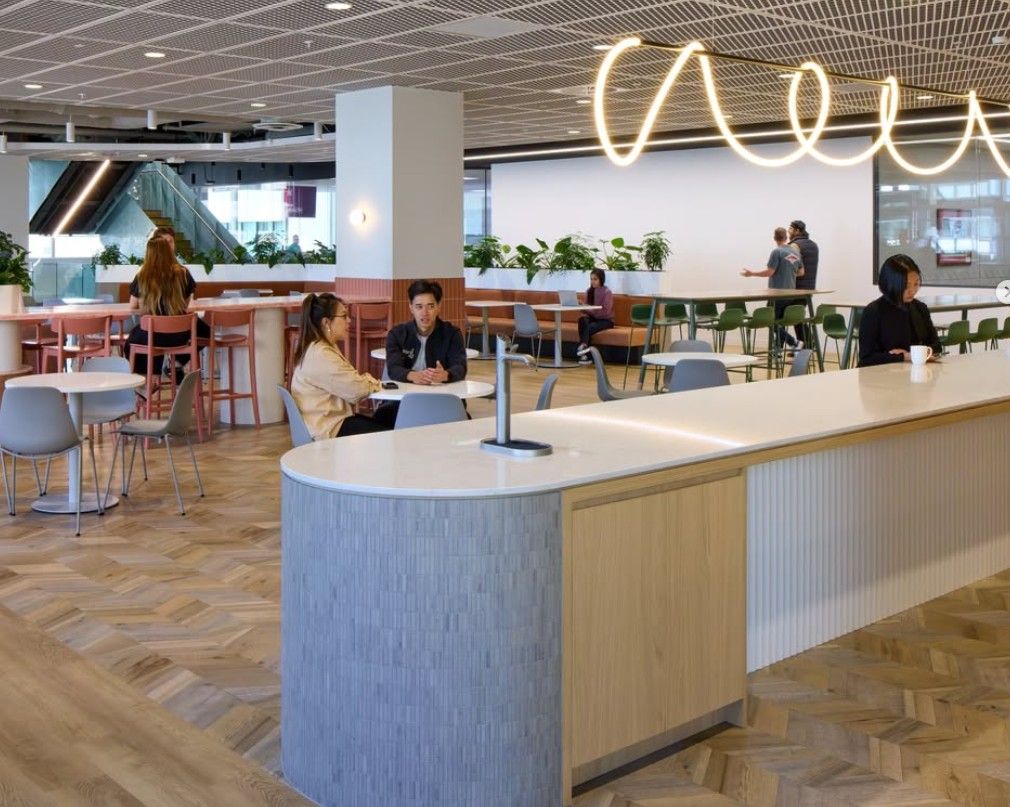 Modern office interior with seating areas, plants, and stylish lighting.