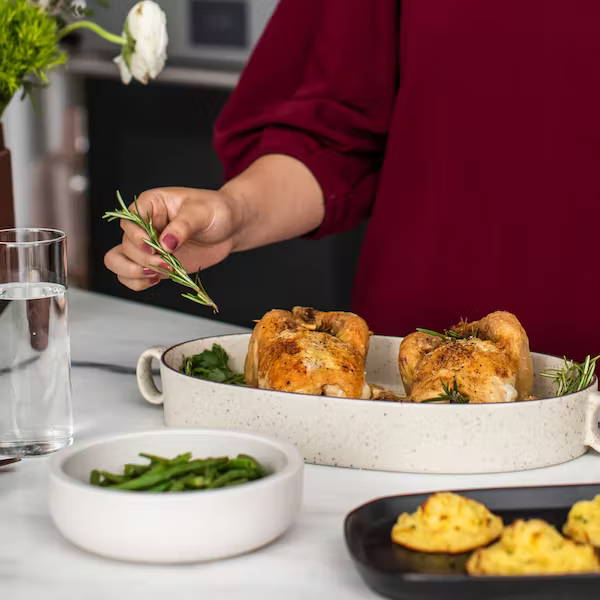 Woman placing rosemary next to Cornish Hens