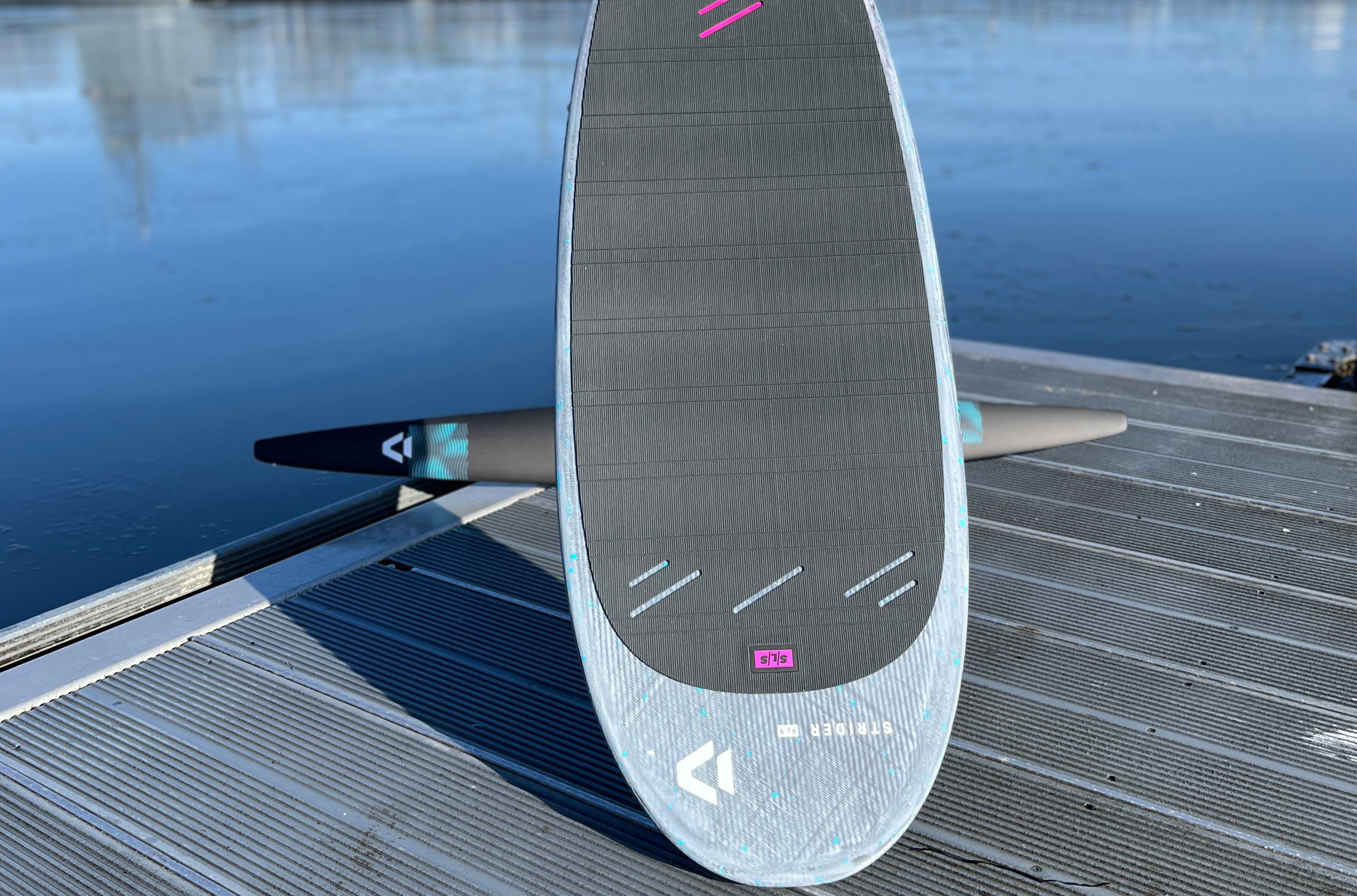A paddleboard on a dock near calm water.