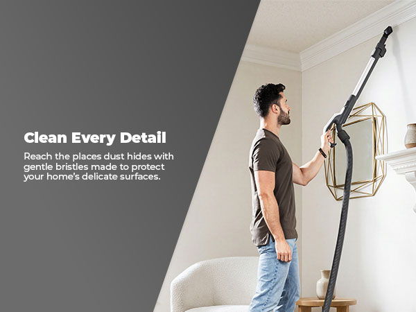 Man using a vacuum cleaner to clean a wall in a modern living room.