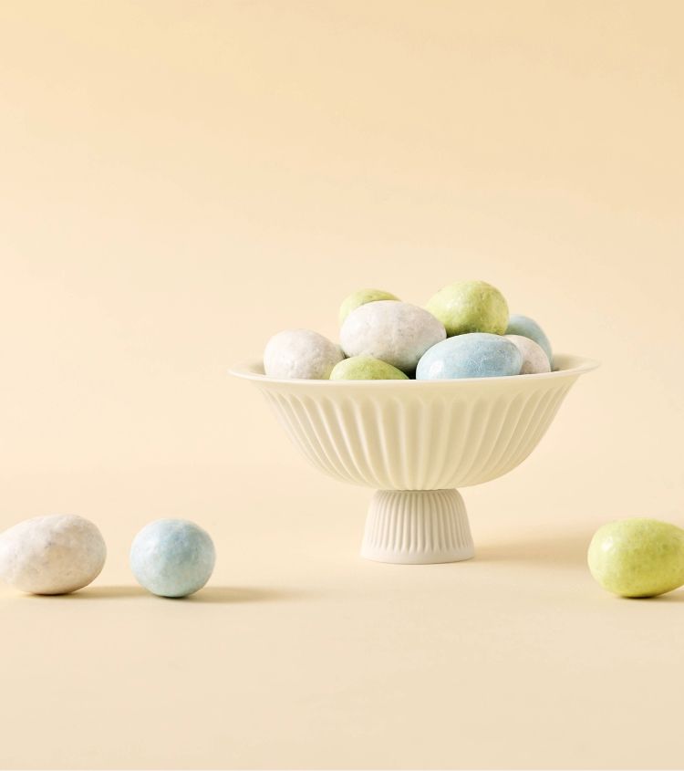 A bowl of pastel-colored eggs on a light background.