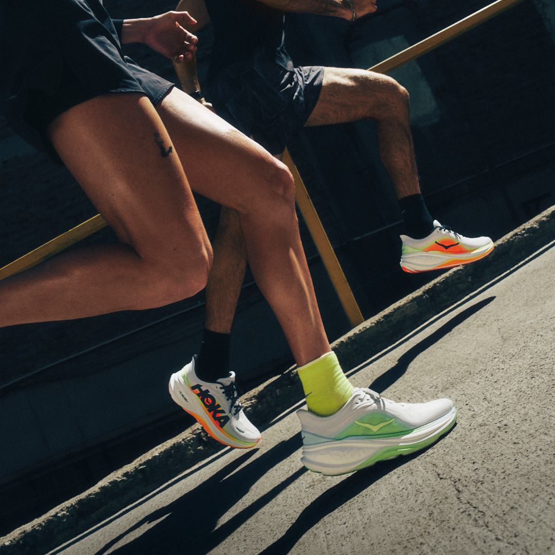 Two runners wearing athletic shoes on a city street.