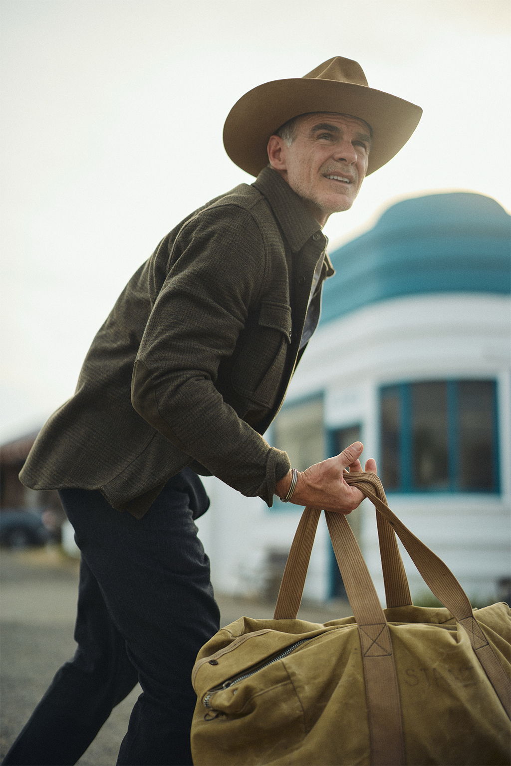 Michael Kelly hitchhiking through Livingston, Montana wearing the Meade Wool Glen Plaid Overshirt in Olive Drab and the Rivay X Alden Bedford Boot in Rough out Suede