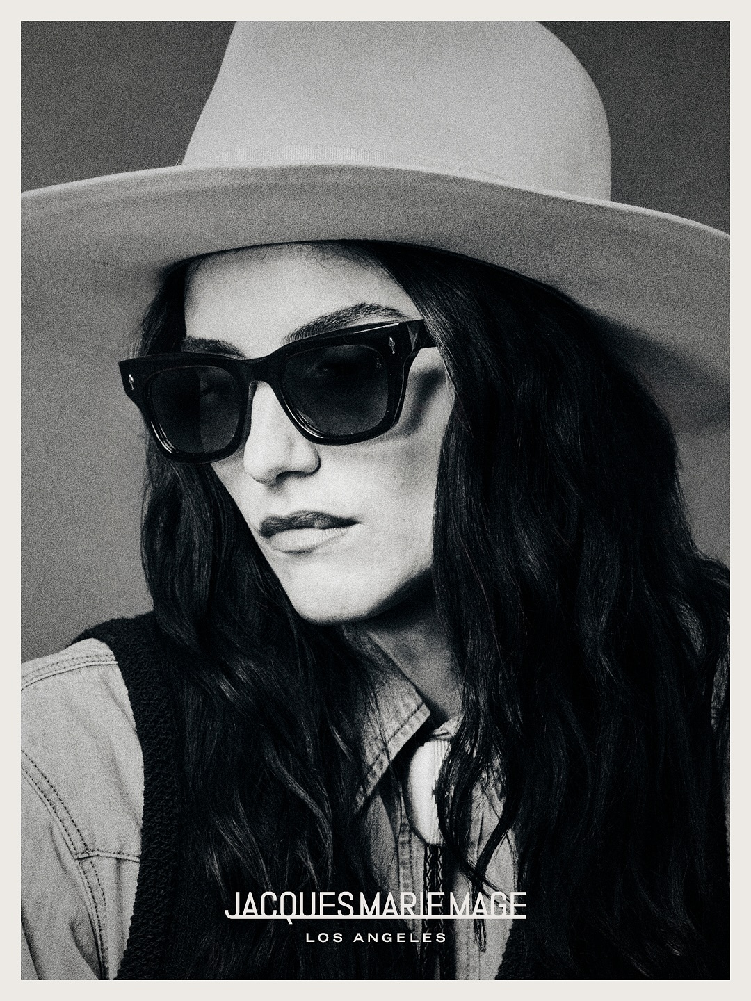 Woman wearing JMM sunglasses and a wide-brimmed hat in black and white.