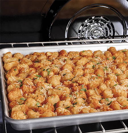 Large pan of delicious tater tots baking in oven.