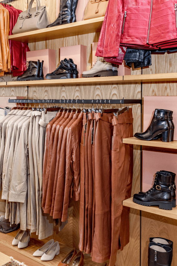 Clothing display featuring various garments and accessories on wooden shelves.