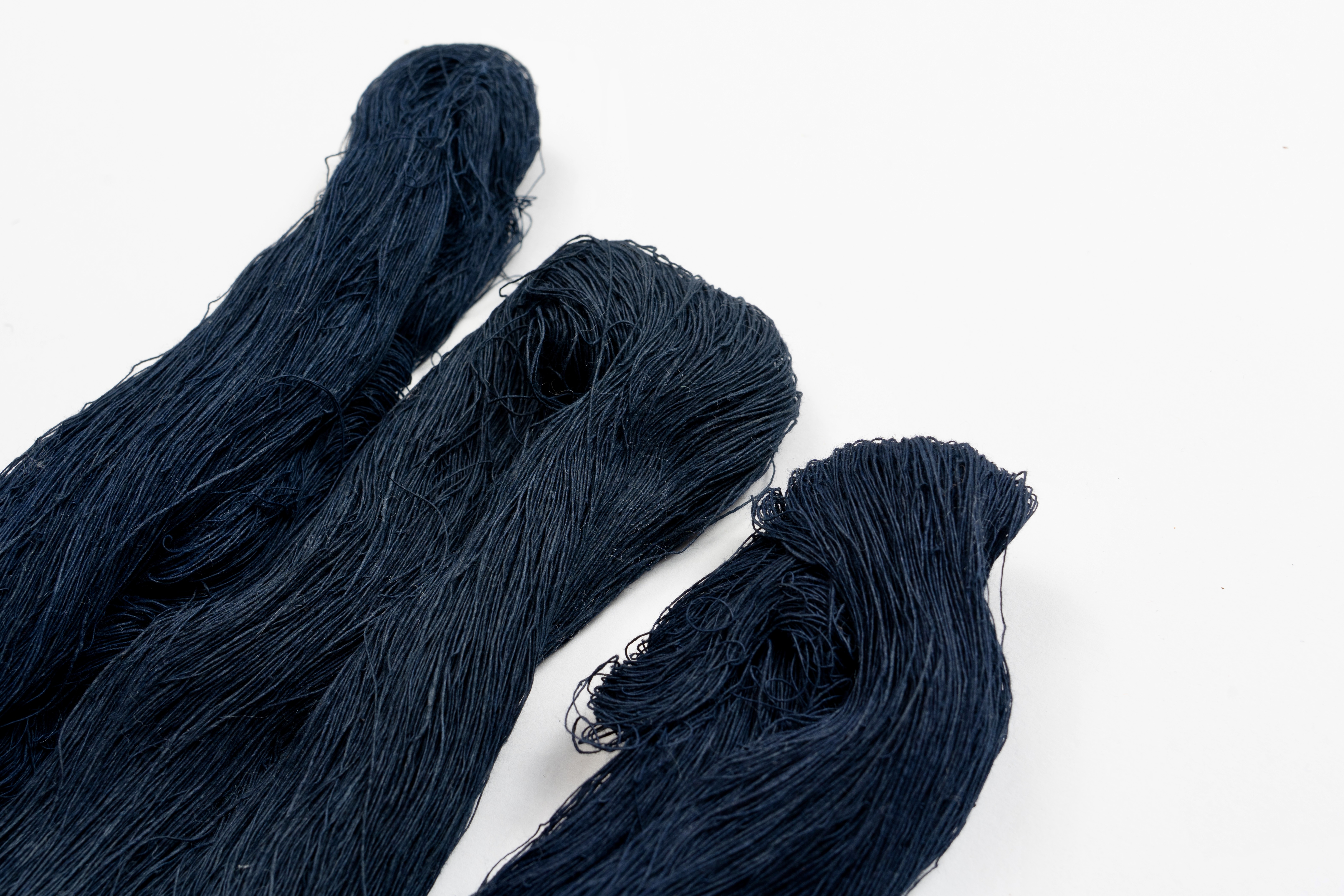 Three dark blue strands of textile fibers on a white background.