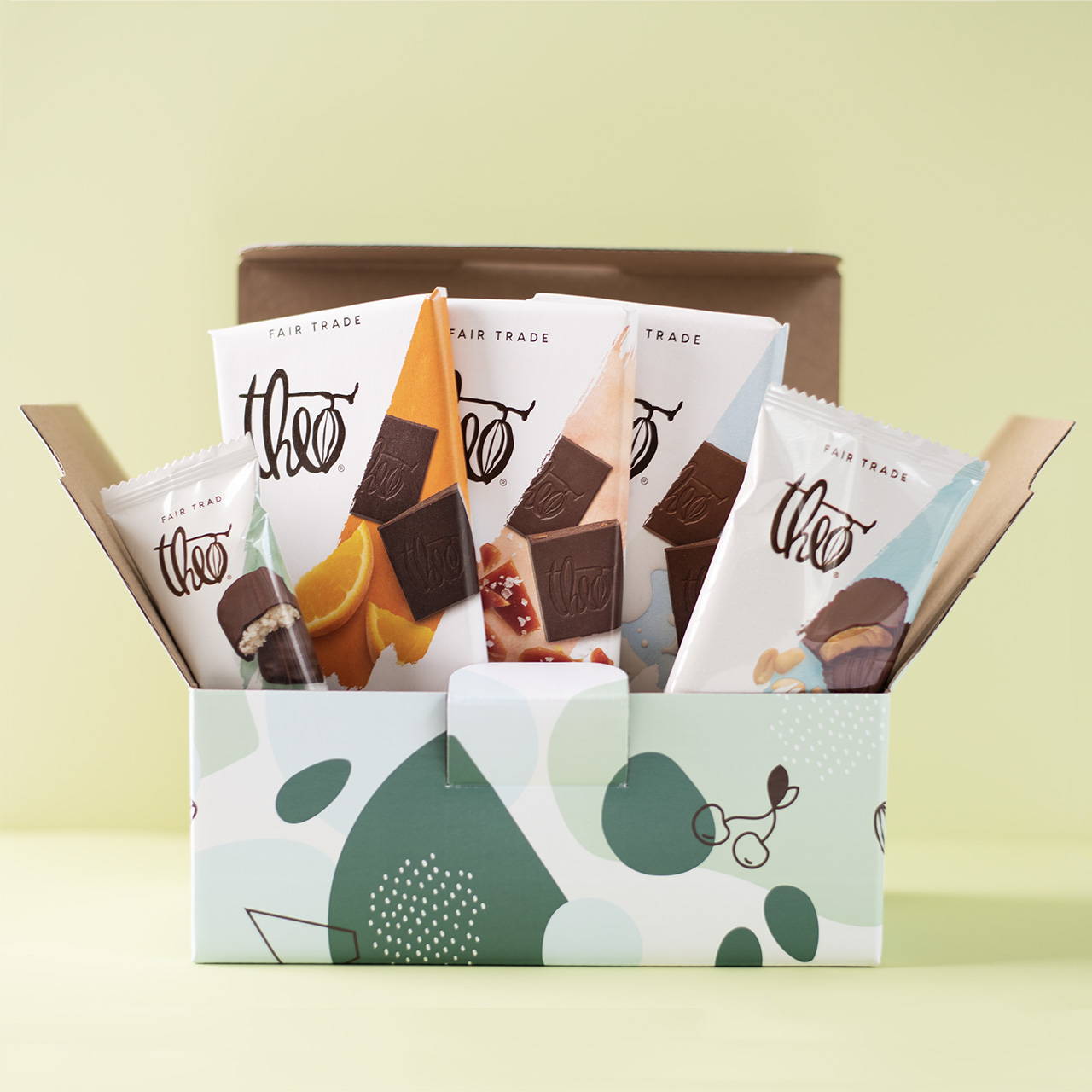 open gift box full of chocolate treats on green background