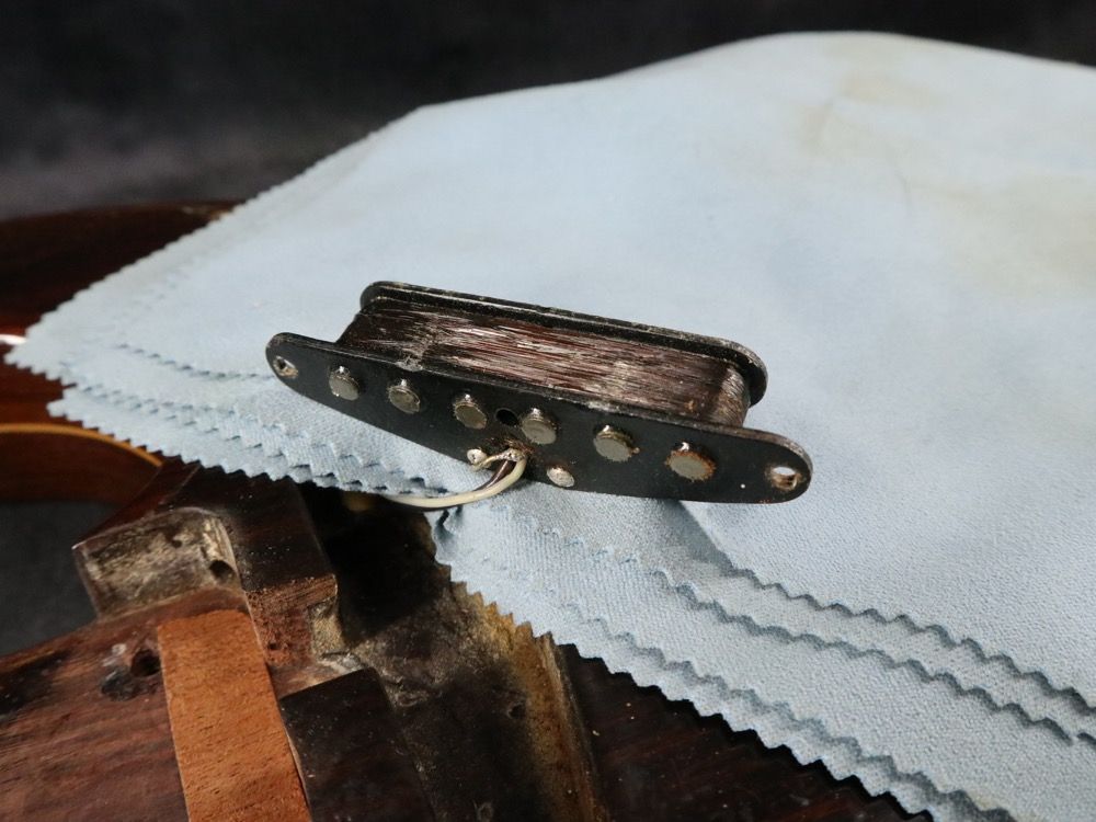A close-up of a guitar pickup resting on a cleaning cloth.
