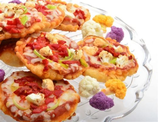 Plate of mini pizzas with colorful vegetables and toppings.