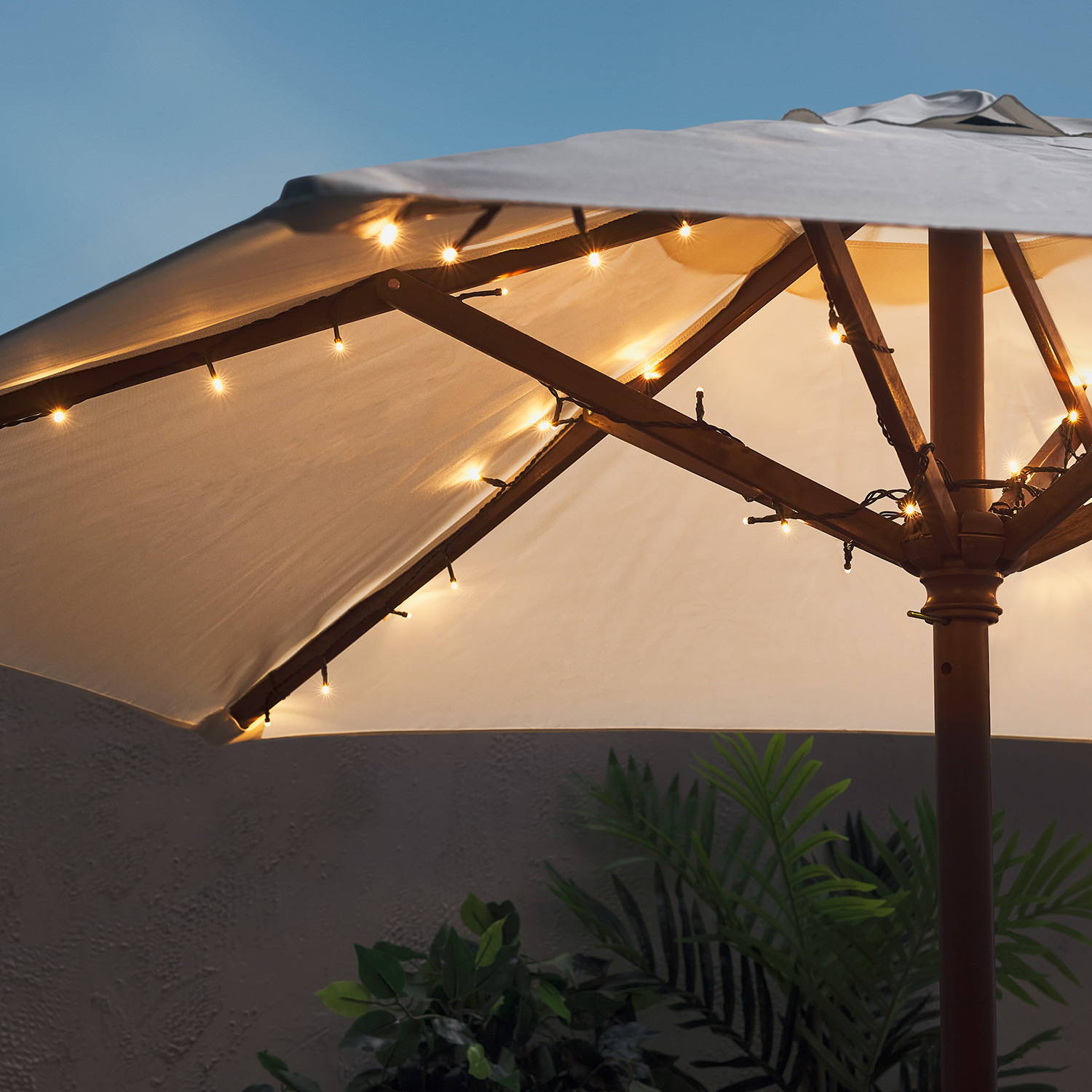Warm white parasol lights entwined beneath a garden parasol