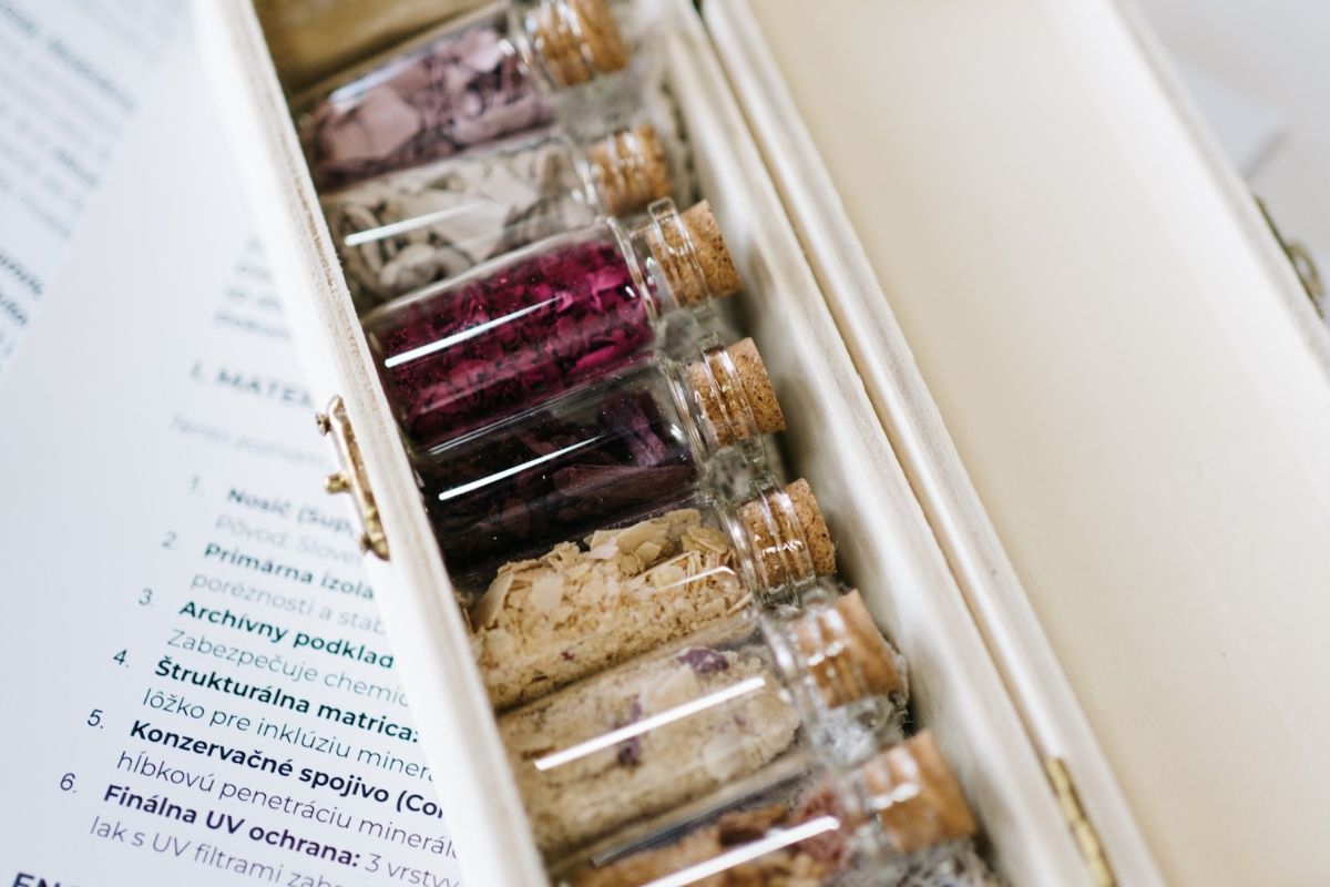 Glass vials with colorful contents arranged in a box.