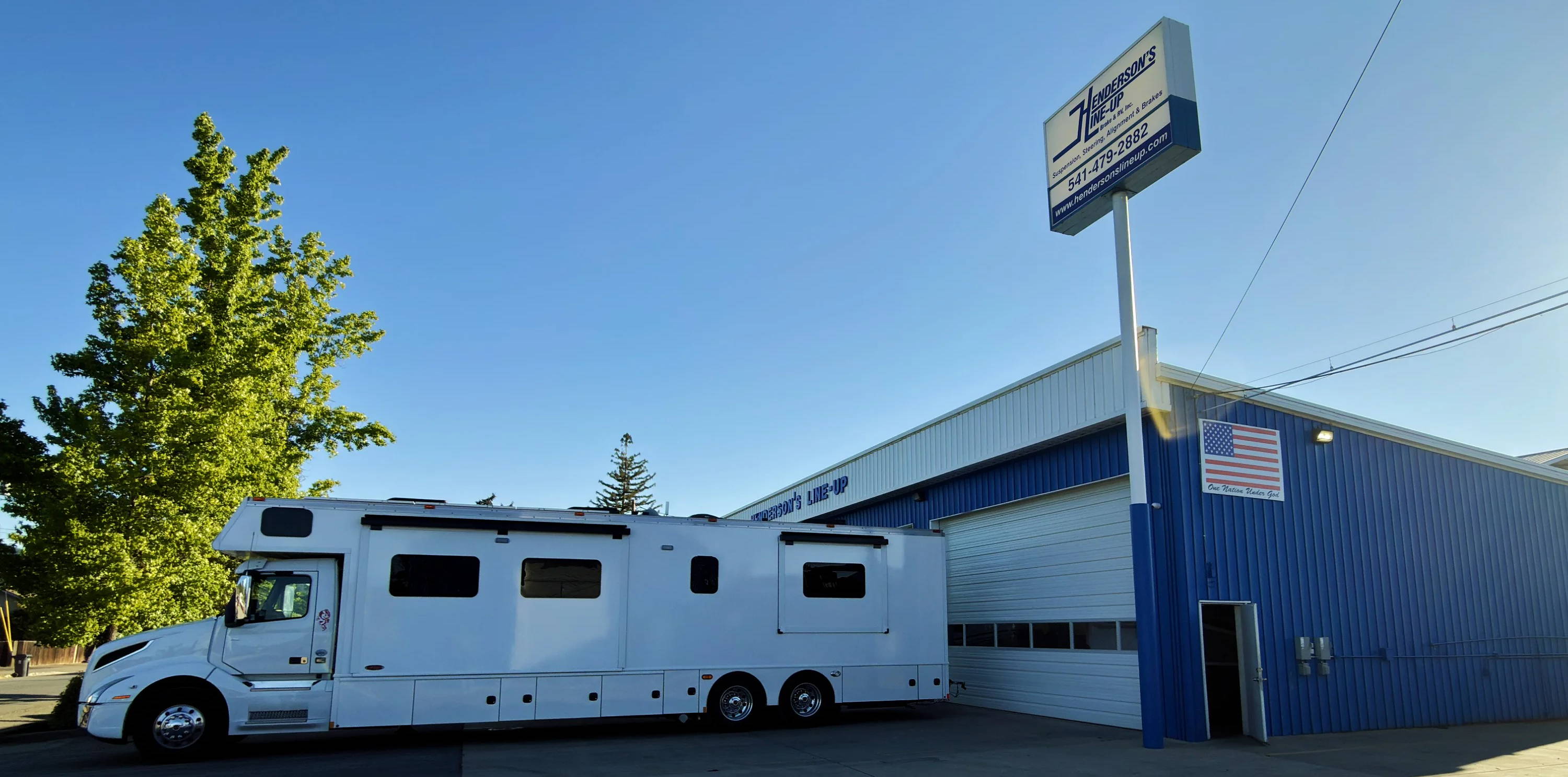 White truck parked beside a blue building under a clear sky.
