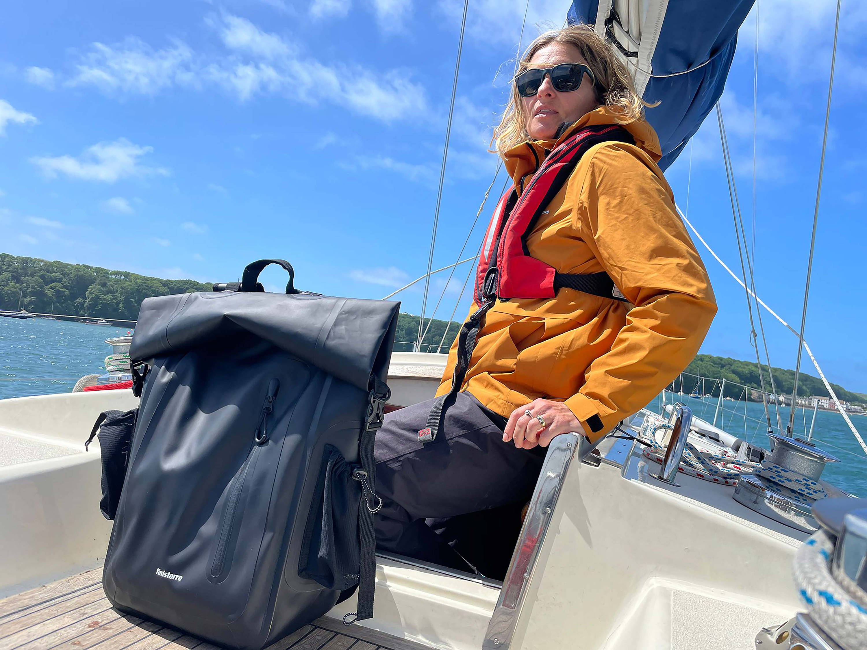 Dr Jo Henley on deck wearing a Finisterre Rainbird and Drift waterproof bag