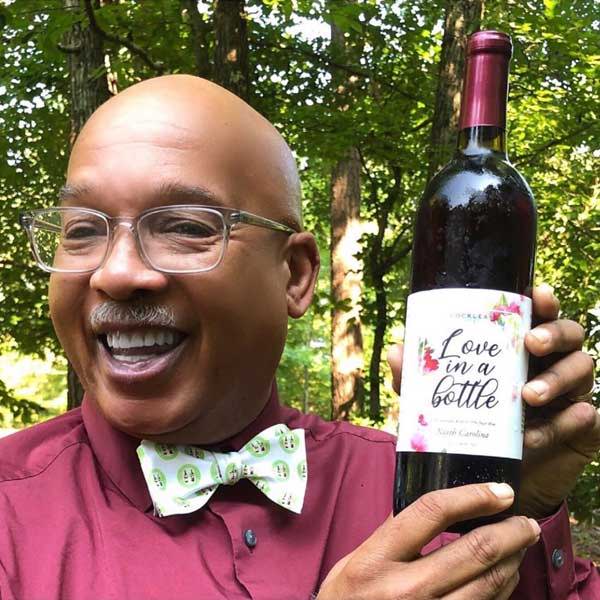 Main wearing logo bow tie holding a bottle of wine