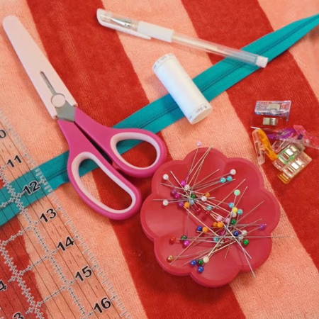 All materials laid out flat towel, zipper, clips, scissors, thread, ruler