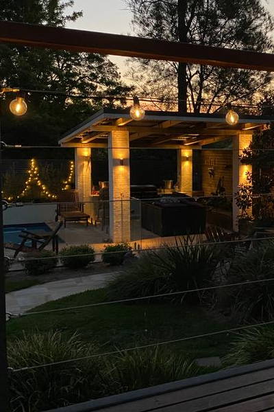 Cozy backyard scene with string lights, trees, and sunset view.