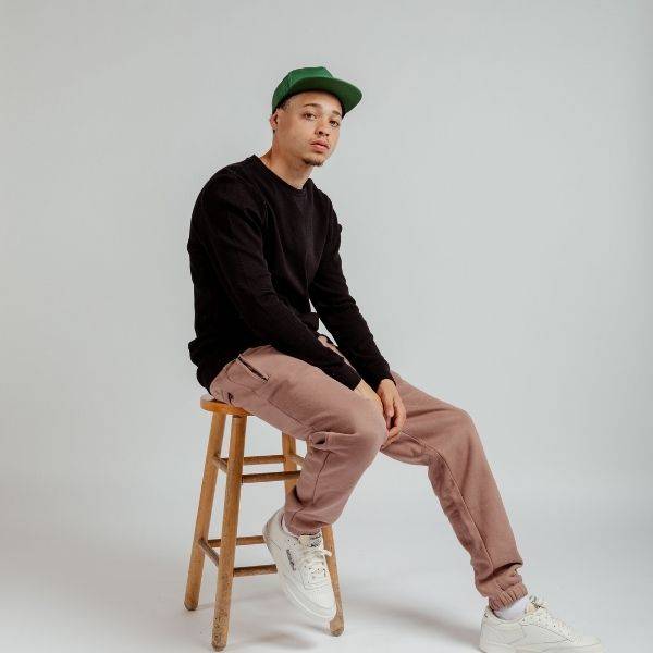 male model wearing maison article clothing and reebok shoes sitting on barstool