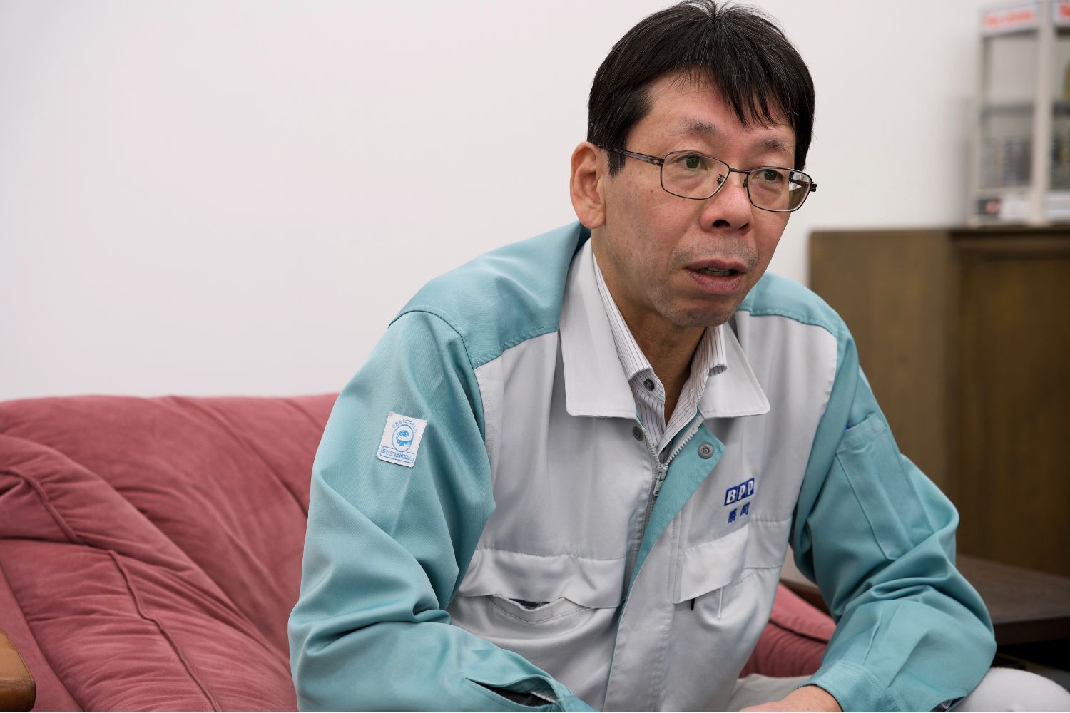 Person in a light blue work shirt sitting on a couch.