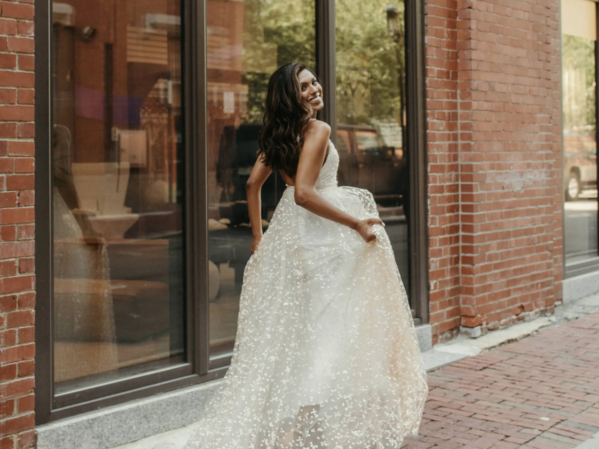 Bride wearing a sparkly Grace Loves Lace wedding dress outside brick building