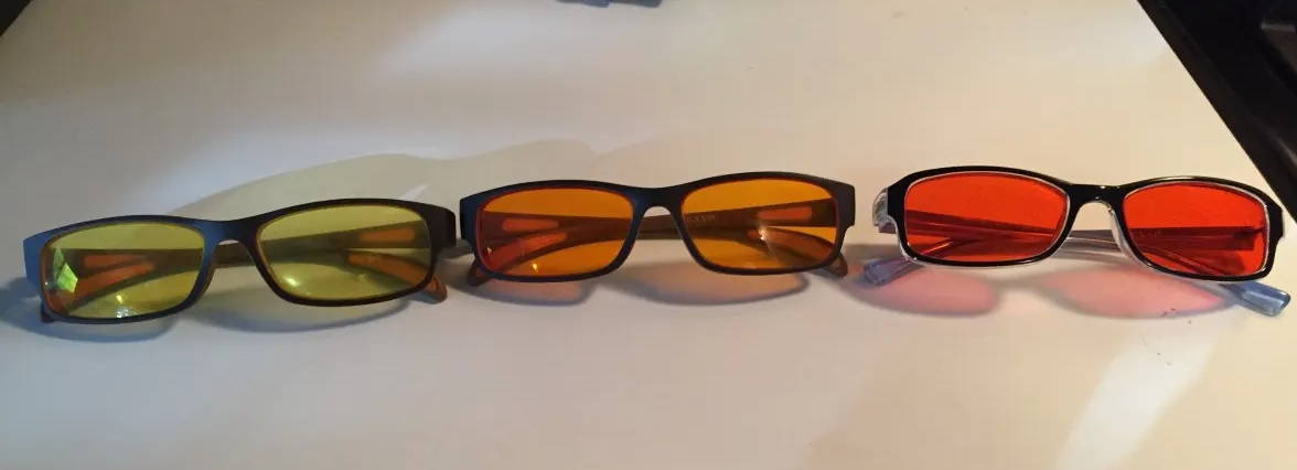 3 different pairs of glasses with yellow lenses, orange lenses and red lenses