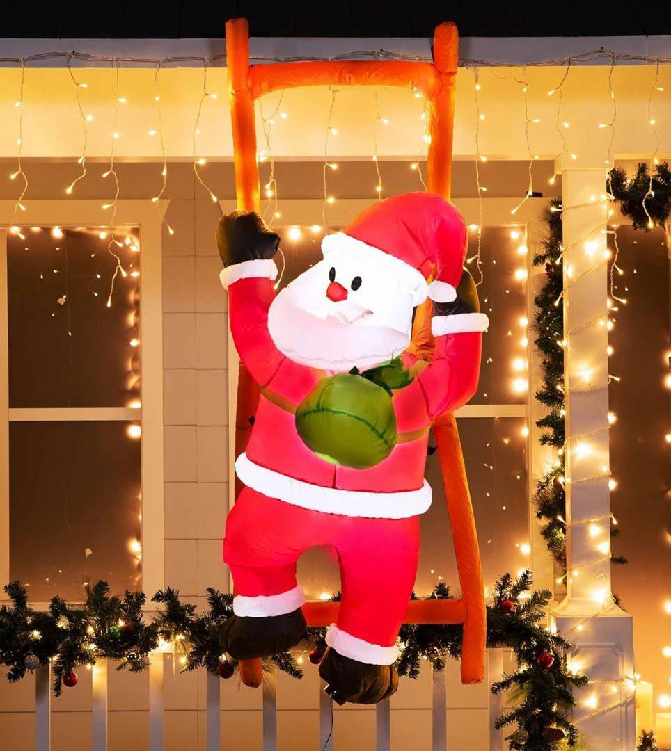 Inflatable Santa climbing Up a ladder on the side of a house