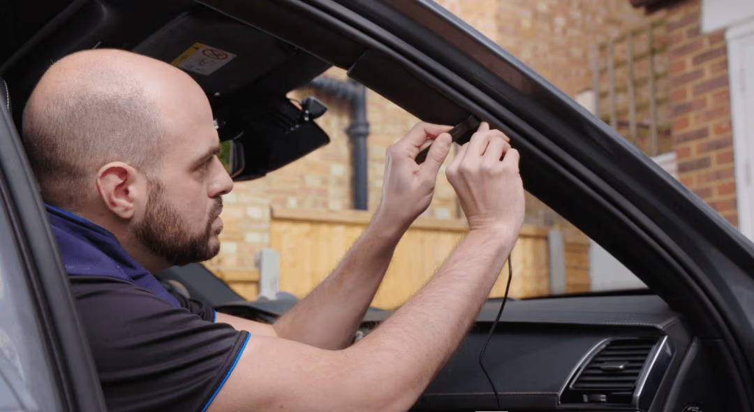 Man installing equipment inside a car.
