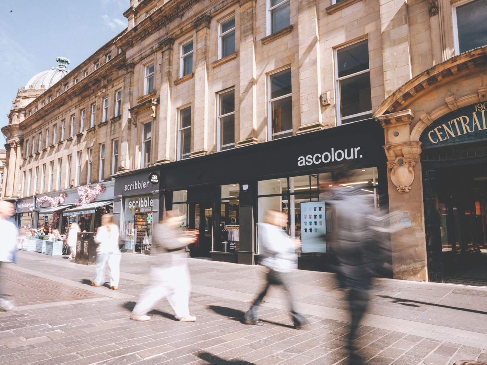 People walking past shops on a busy street.