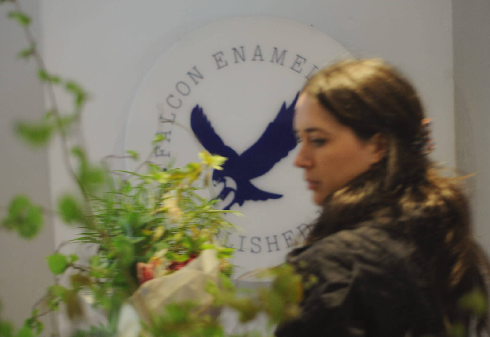 Paris Alma carrying flower in fornt of the blue and white Falcon wall display sign.