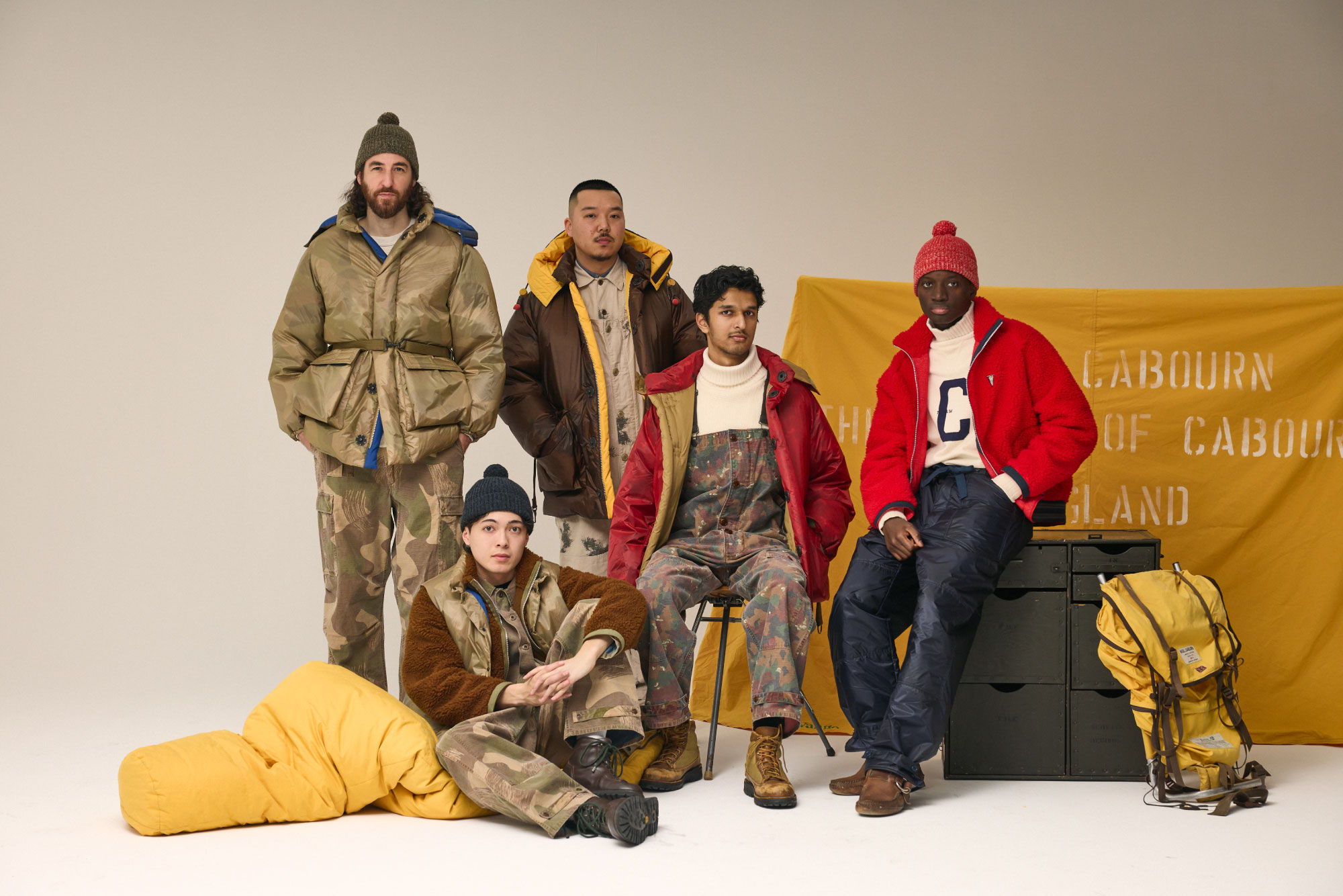 A group of five people in winter clothing, posing indoors.