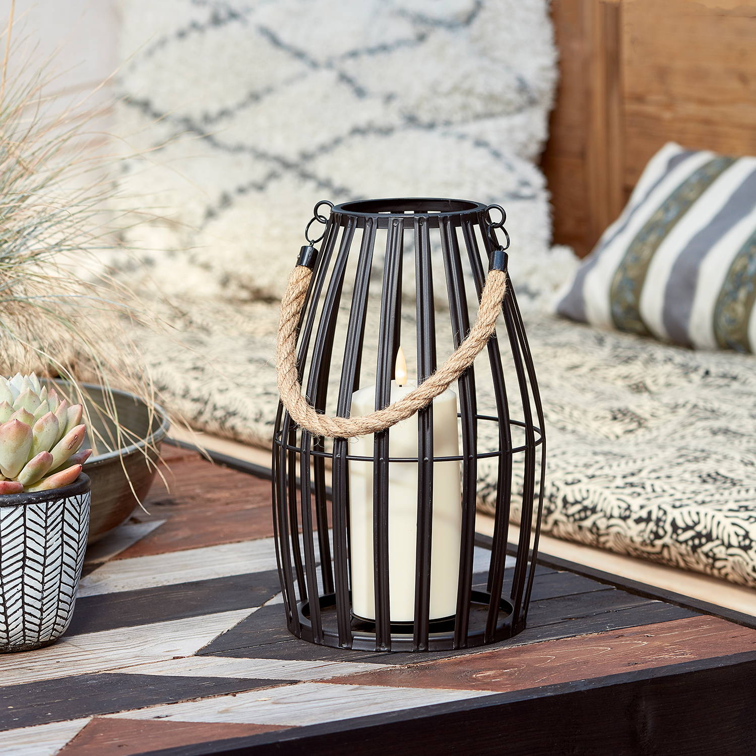 Black lantern and LED candle in an outdoor seating setting