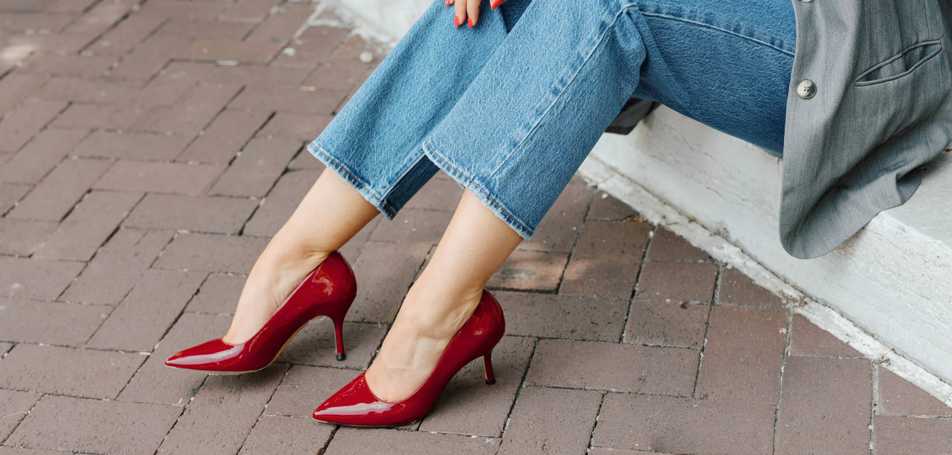 A pair of red high heels worn with cropped jeans.