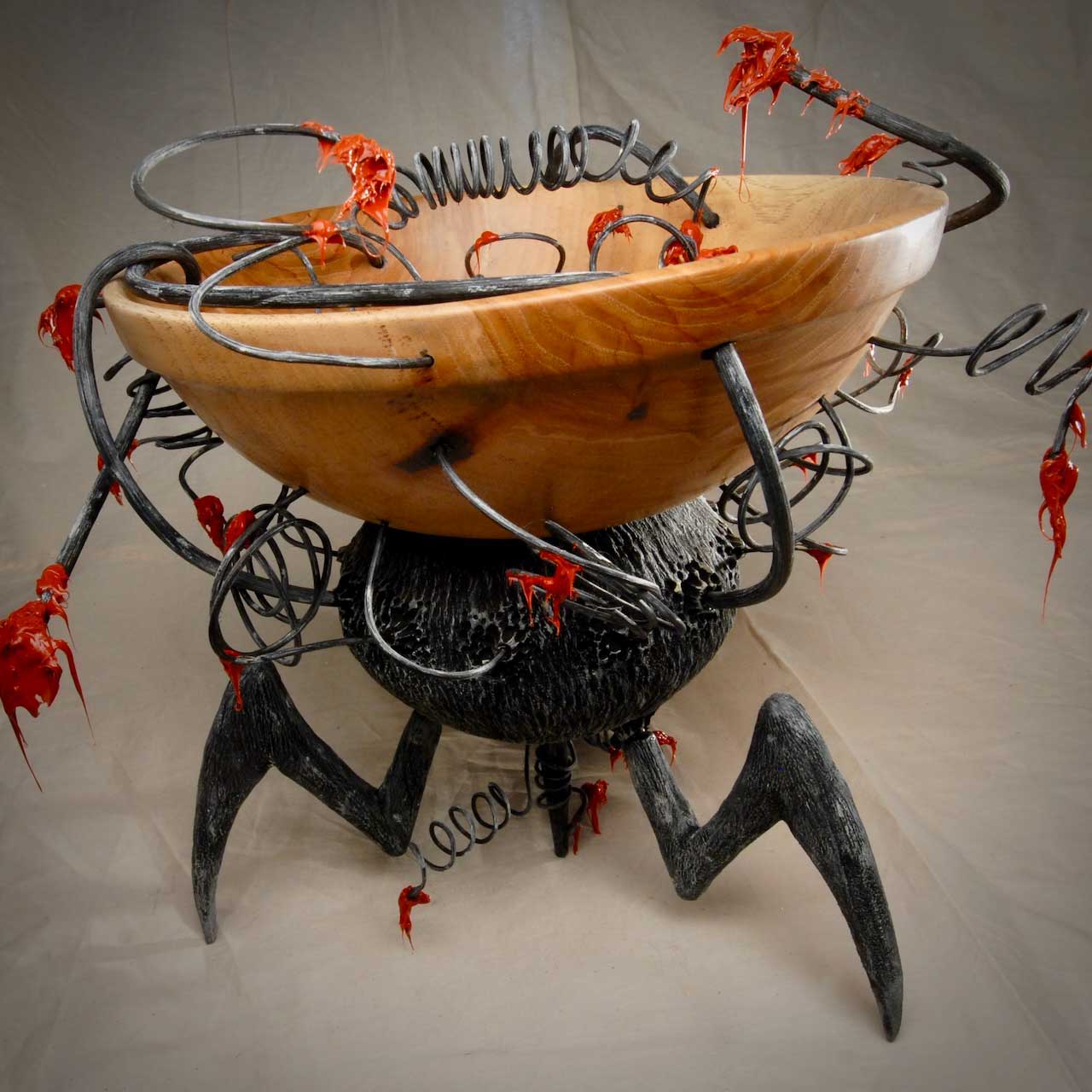 A wooden bowl with metal tentacles and red decorations.