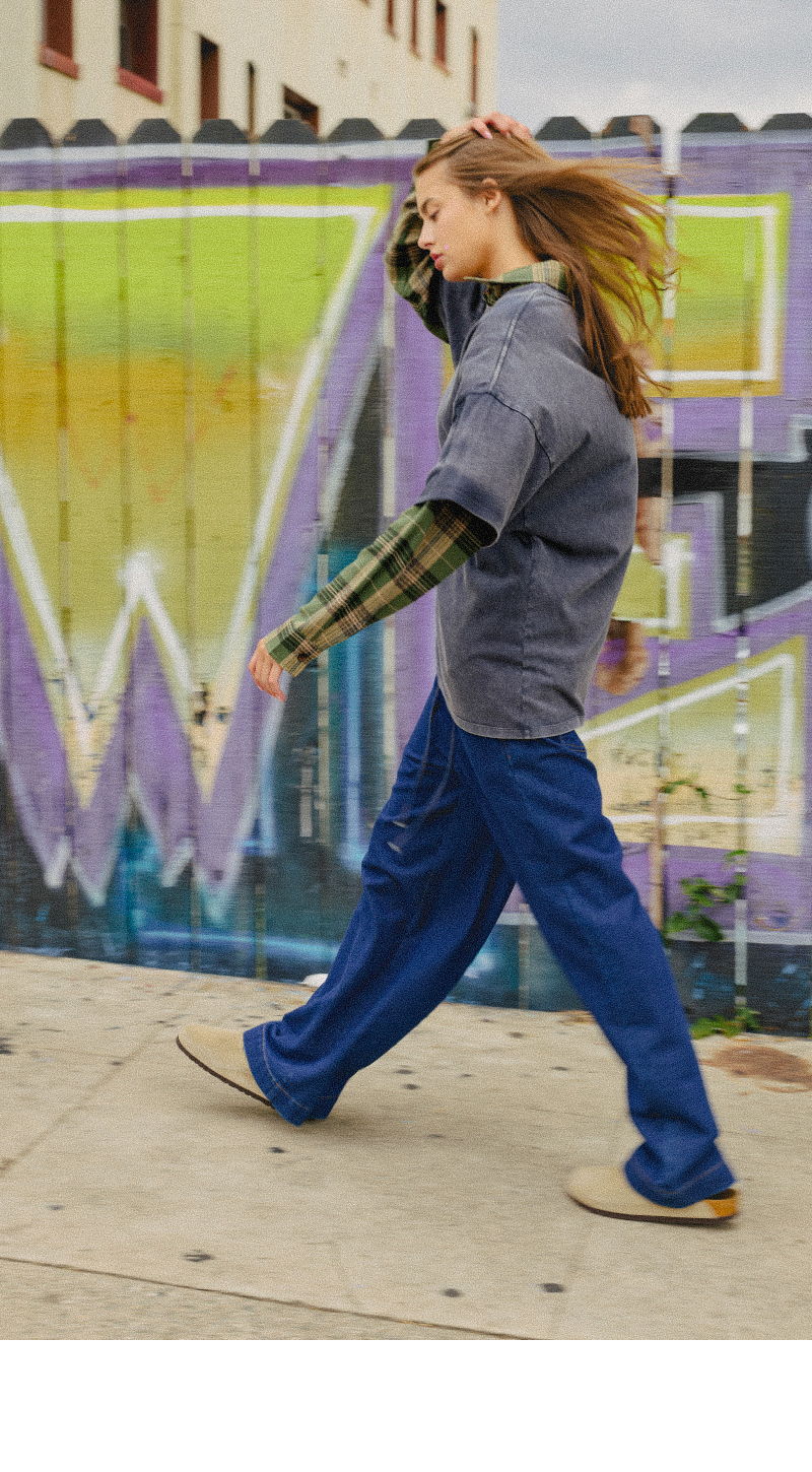 A person walks past a colorful graffiti wall, wearing casual clothing.