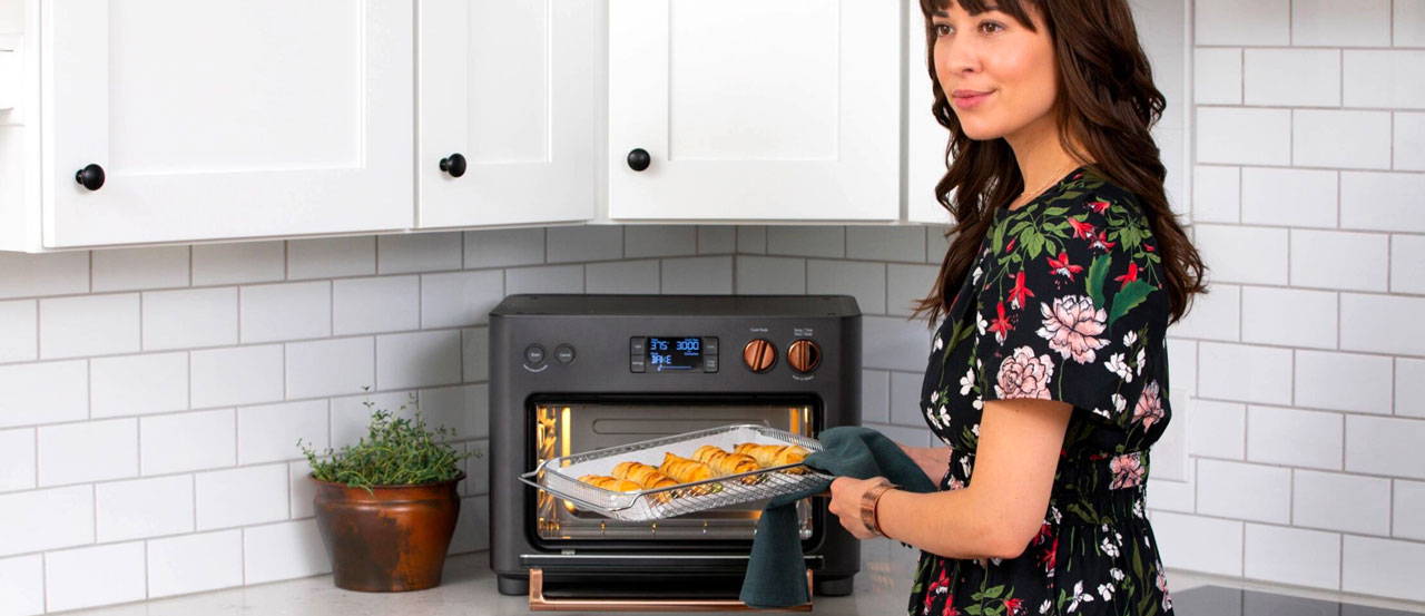 Woman getting puff pastry wrapped asparagus out of couture oven