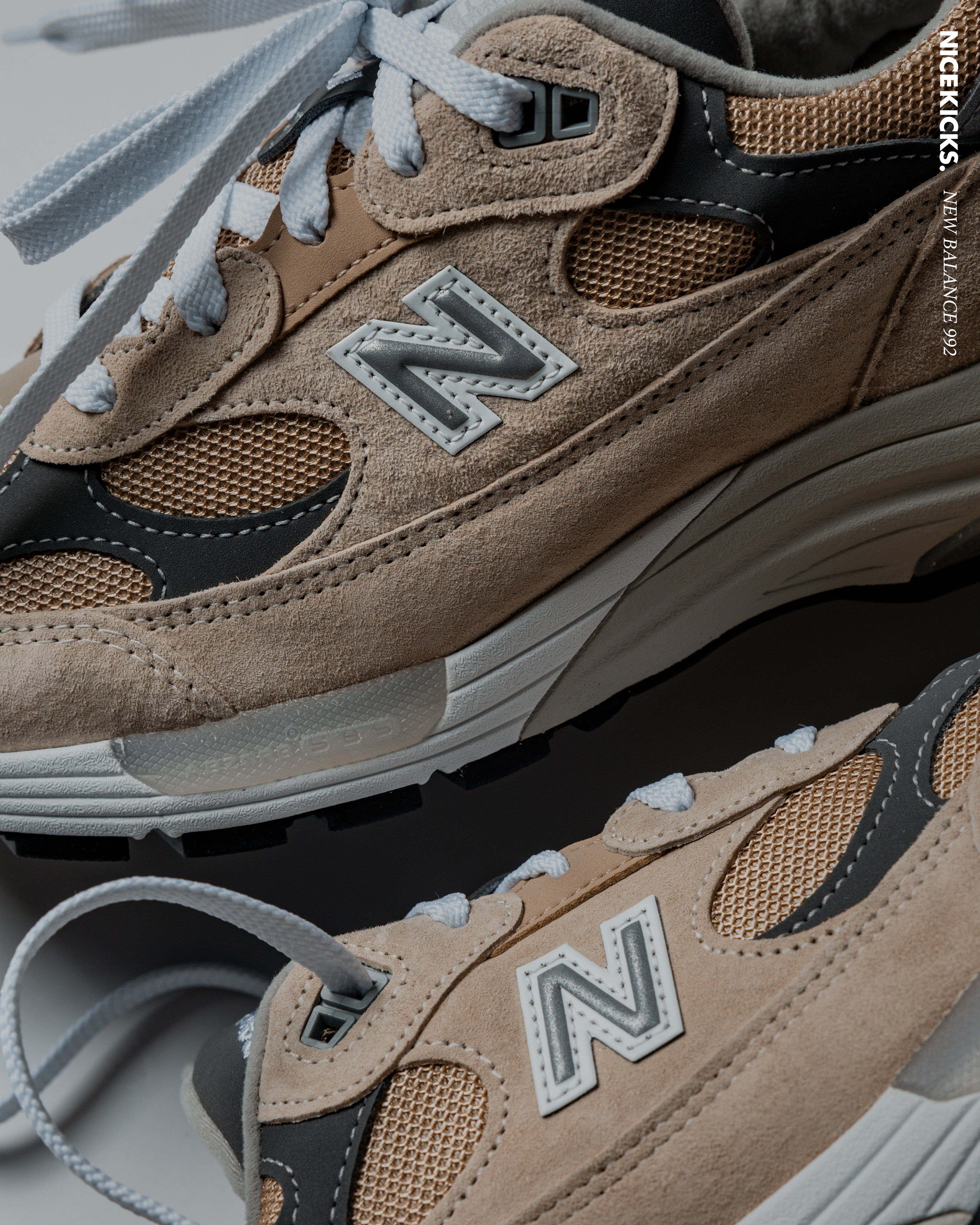 Close-up of beige and gray New Balance sneakers on a neutral background.