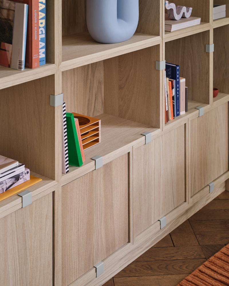 Wooden Stacked shelving unit by Muuto with books and decorative items.