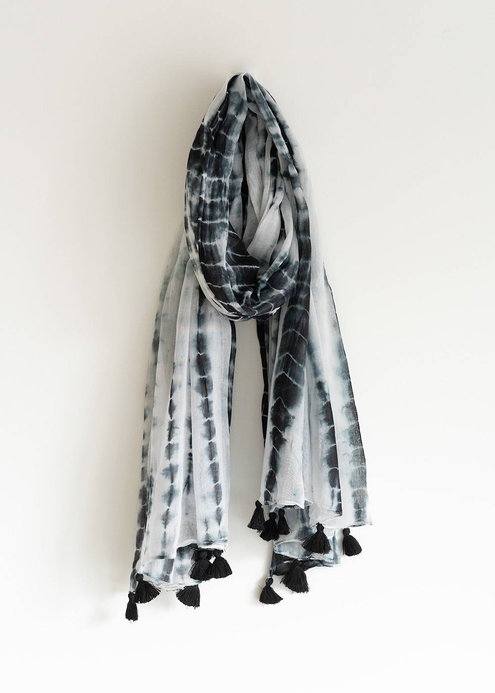 A dark blue and white tie dye scarf with matching tassles.