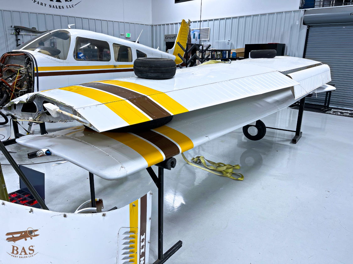 Aircraft wing with yellow and brown stripes in a hangar.