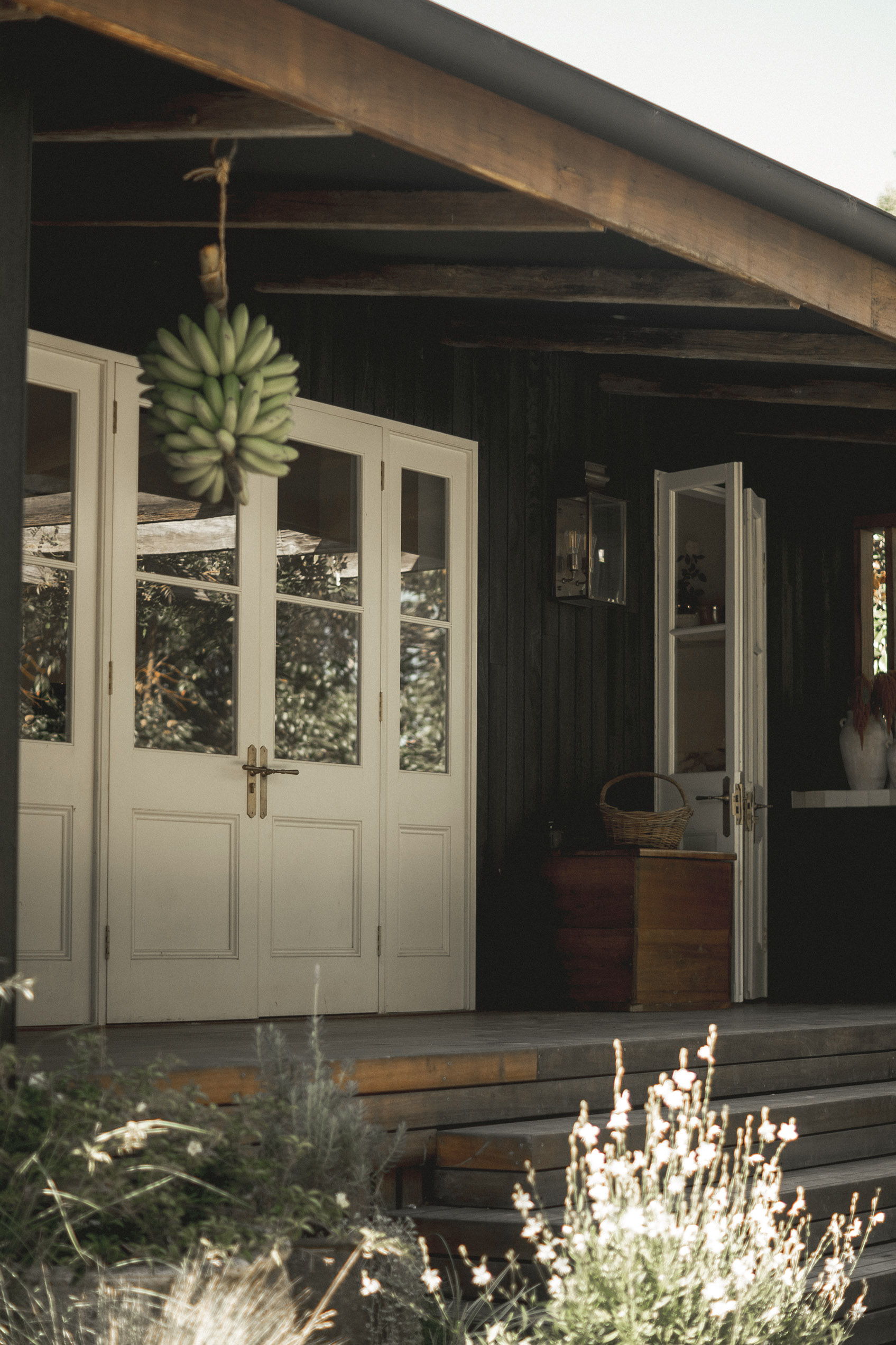 A rustic entrance with double doors and hanging bananas.
