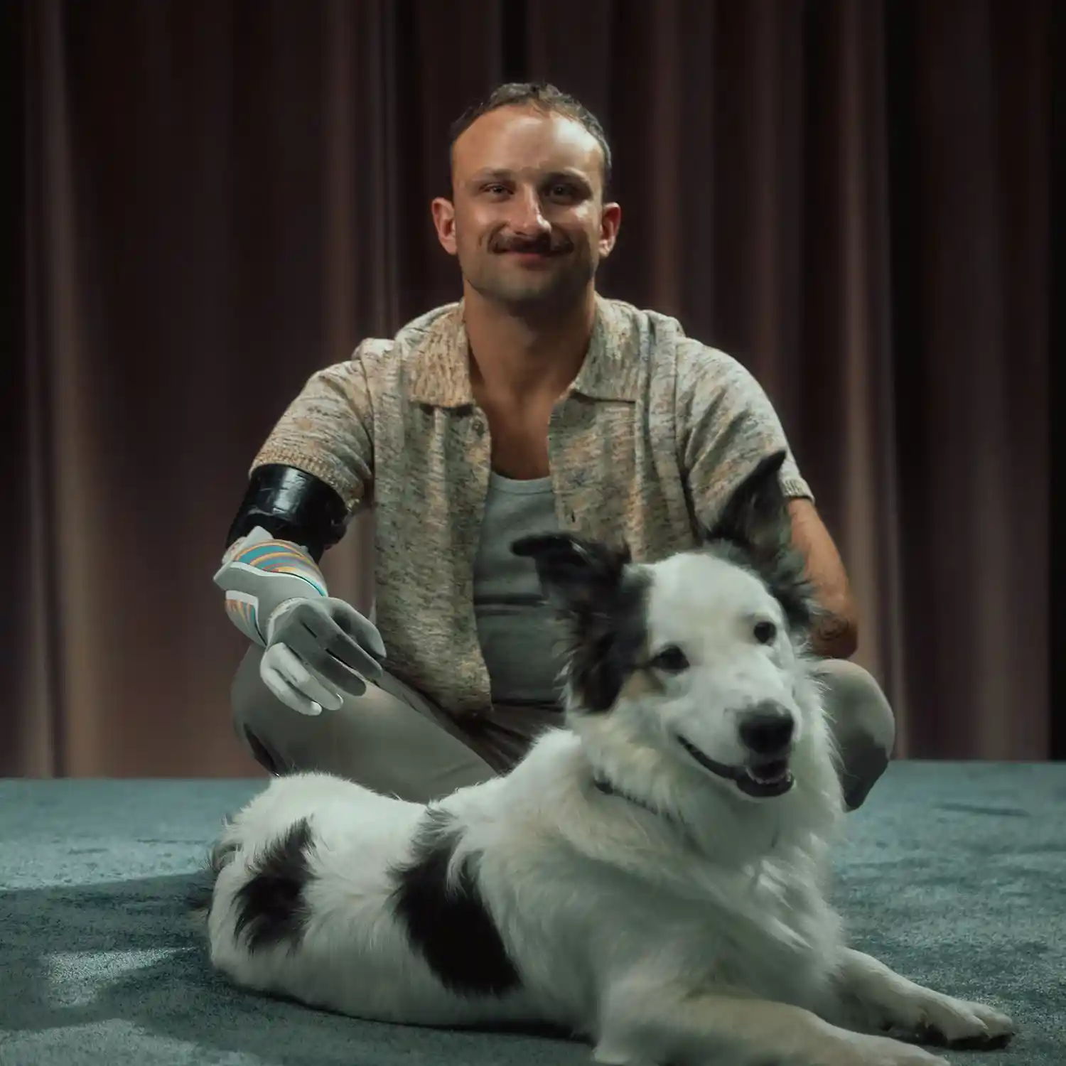 piotr sajdak sitting on the floor with his legs crossed. A dog is sitting in front of him
