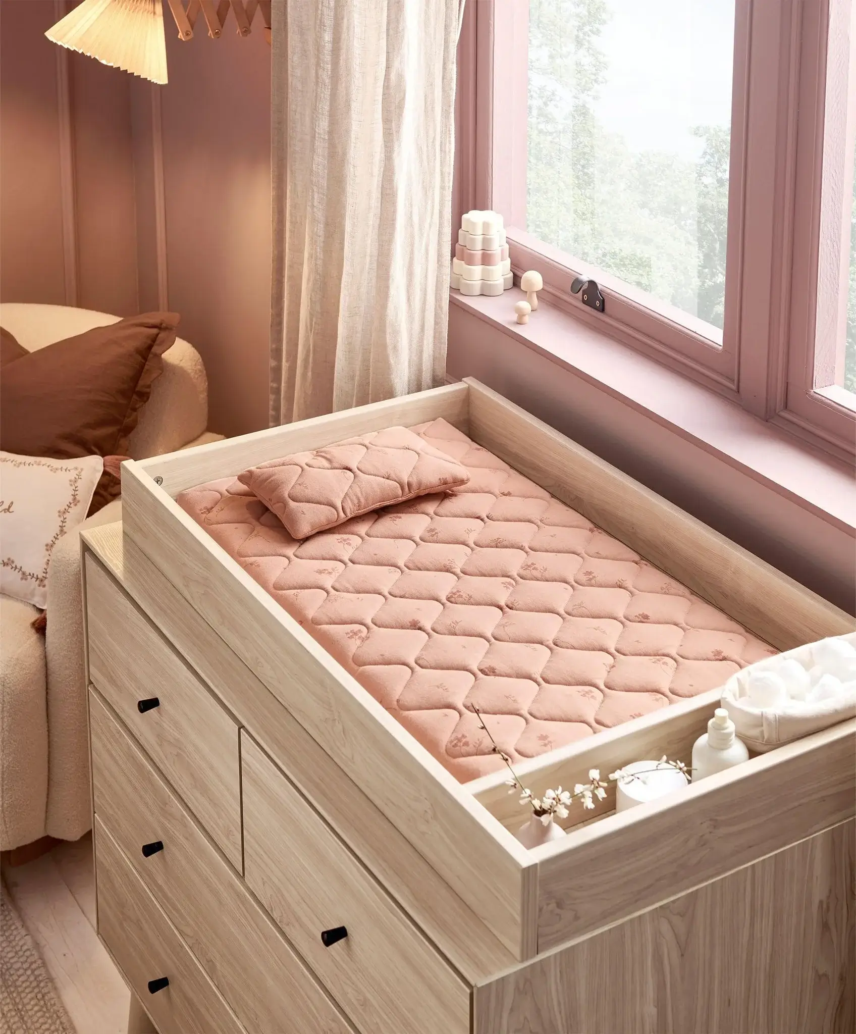 A cozy changing table with a soft pink mat and decorative items.