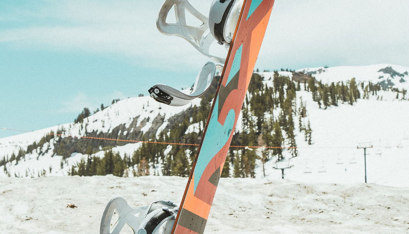 A colorful snowboard standing in a snowy landscape with mountains in the background.