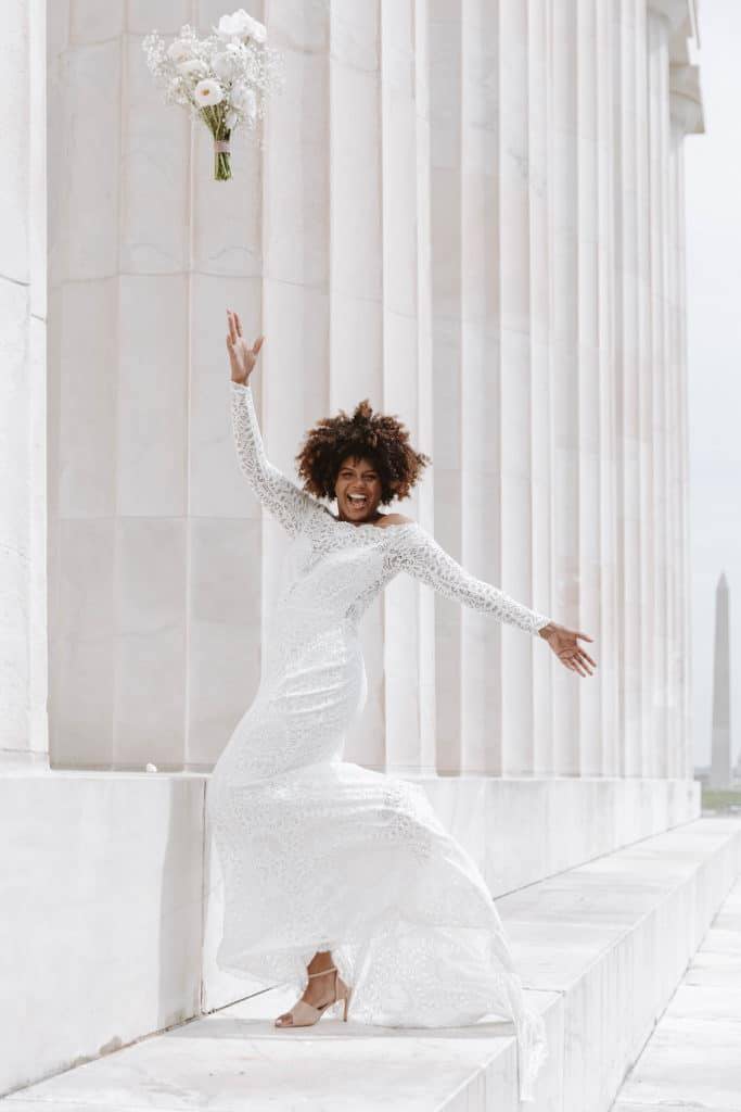 Bride out front of white sandstone building wearing her bridal gown