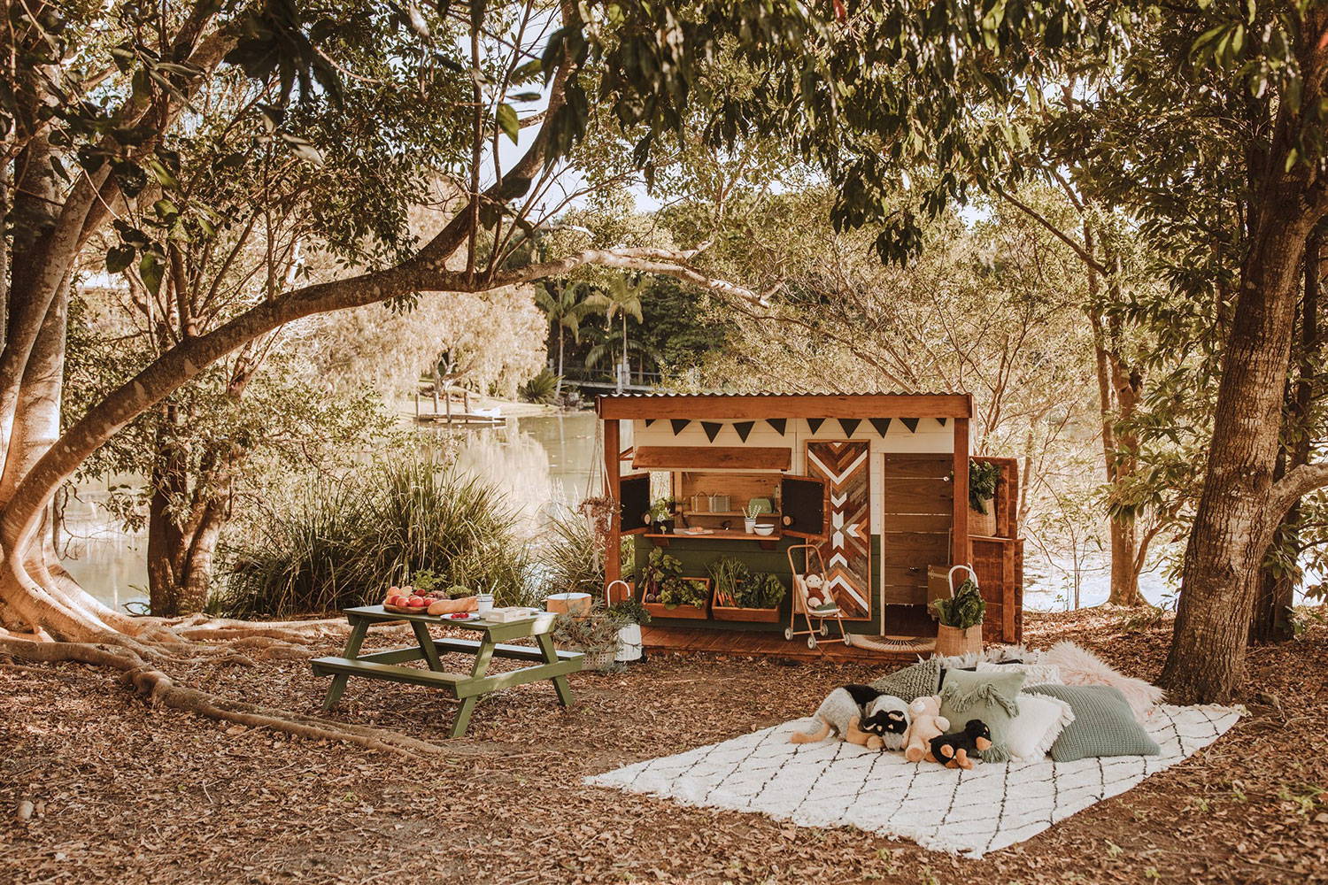 Timber cubby house with verandah and picnic table next to lake