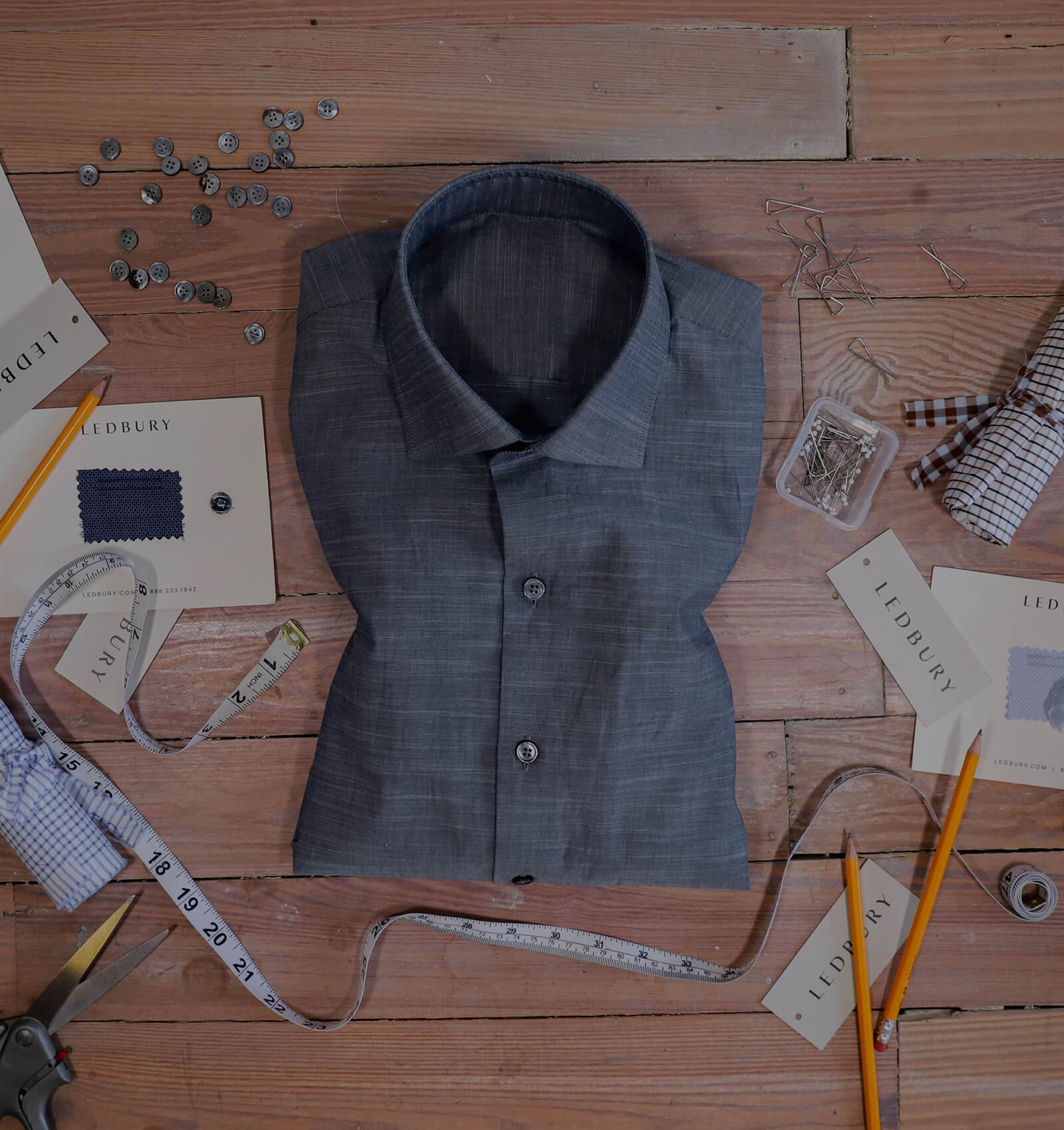 Men's slate blue chambray dress shirt folded on a desk 